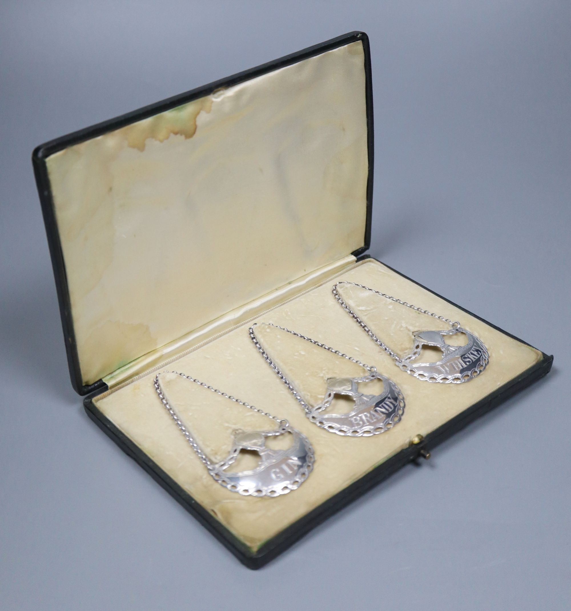 A cased set of three silver wine labels by Daniel & John Wellby, London, 1911, 5cm, 29 grams,